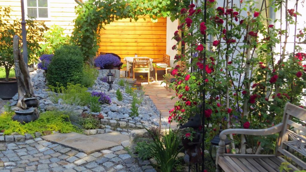 韦尼格罗德Ferienwohnung Wolfsholz的鲜花盛开的花园,房子前面的长凳