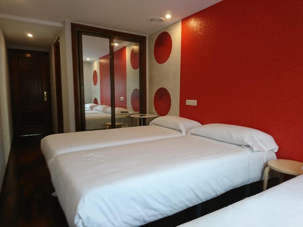拉科鲁尼亚Saudade Hostal Cafetería的红色墙壁的酒店客房内的两张床