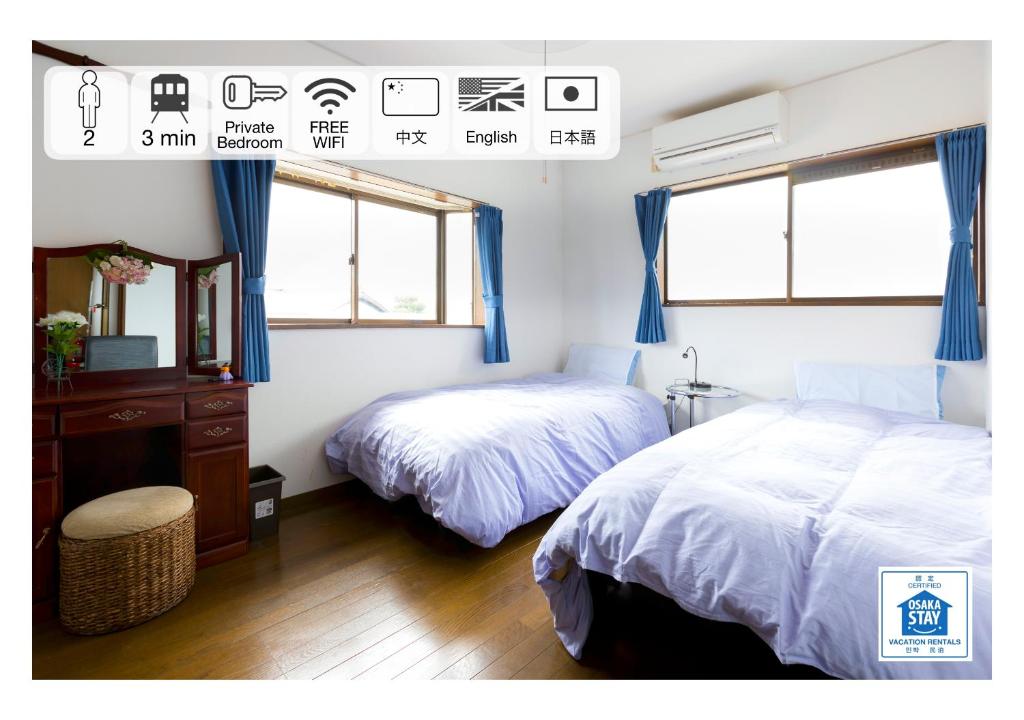 贝冢市A＆Z民宿的一间卧室设有两张床、一个梳妆台和两个窗户。