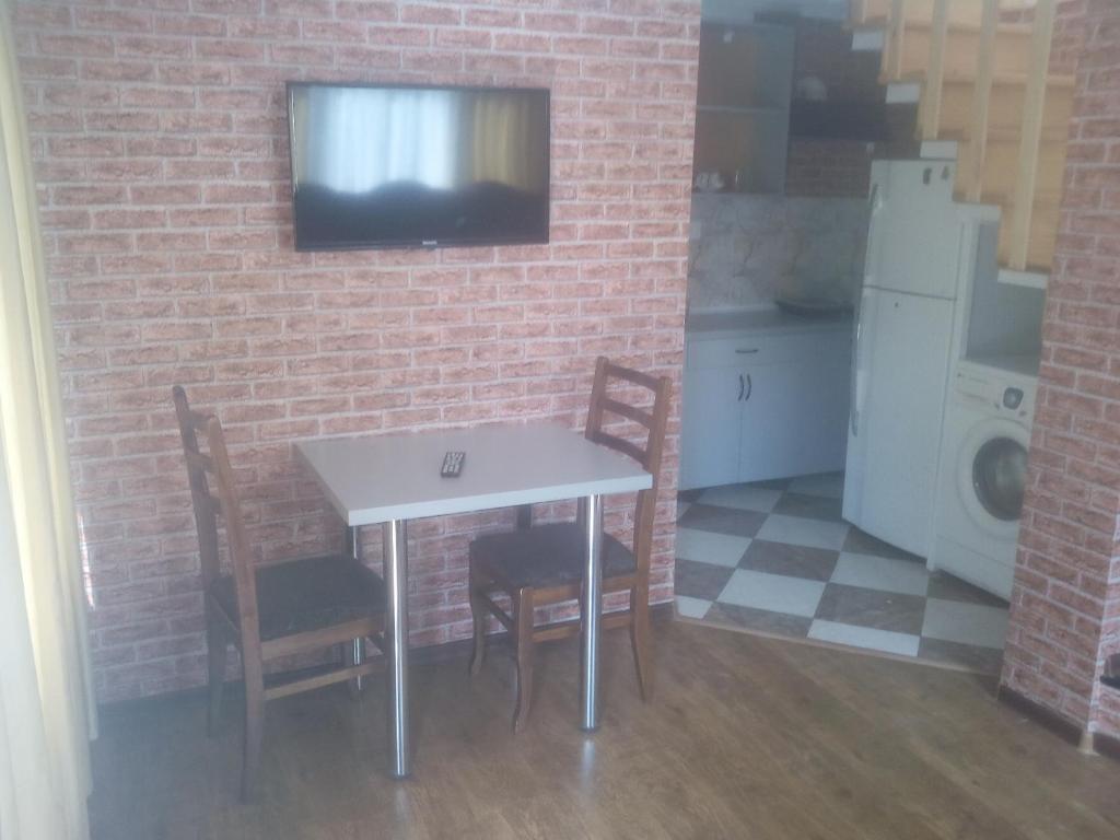 库塔伊西malu的厨房配有桌椅,砖墙上配有电视