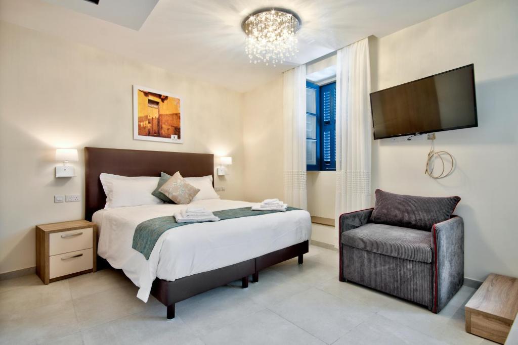 KirkopThe Suites – Piazza Kirkop的一间卧室配有一张床和一把椅子