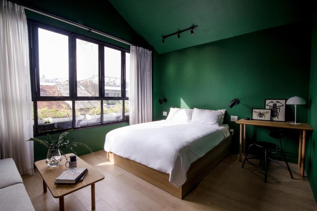 胡志明市Botanist Lab Minihotel by CIRCADIAN的绿色卧室配有床和桌子