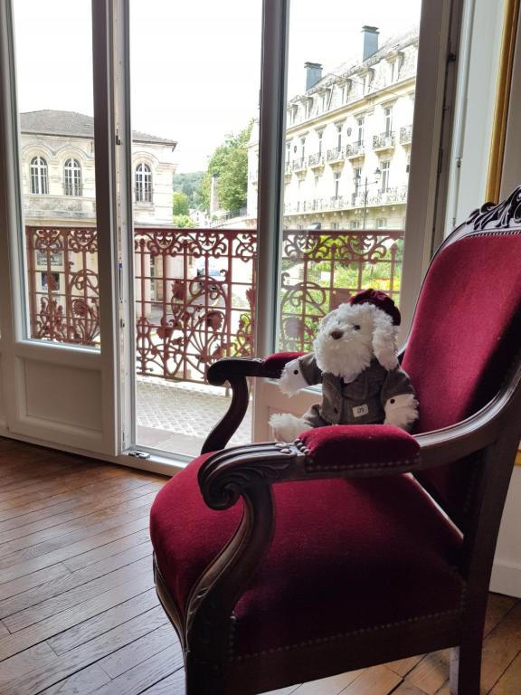 普隆比埃莱班Tradition Plombières的坐在窗边椅子上的泰迪熊