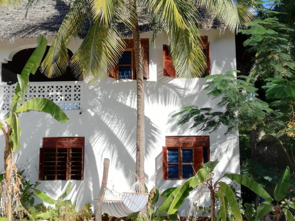 江比阿Furaha Lodge的一间白色的房子,设有窗户和棕榈树