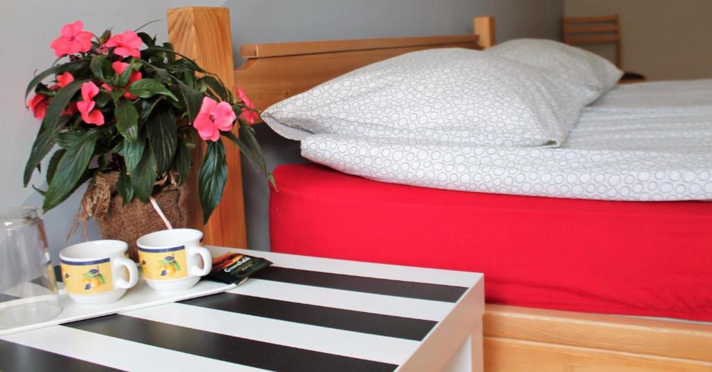 利耶帕亚Liepu Hostelis的一张带两个咖啡杯的床和一张带鲜花的桌子