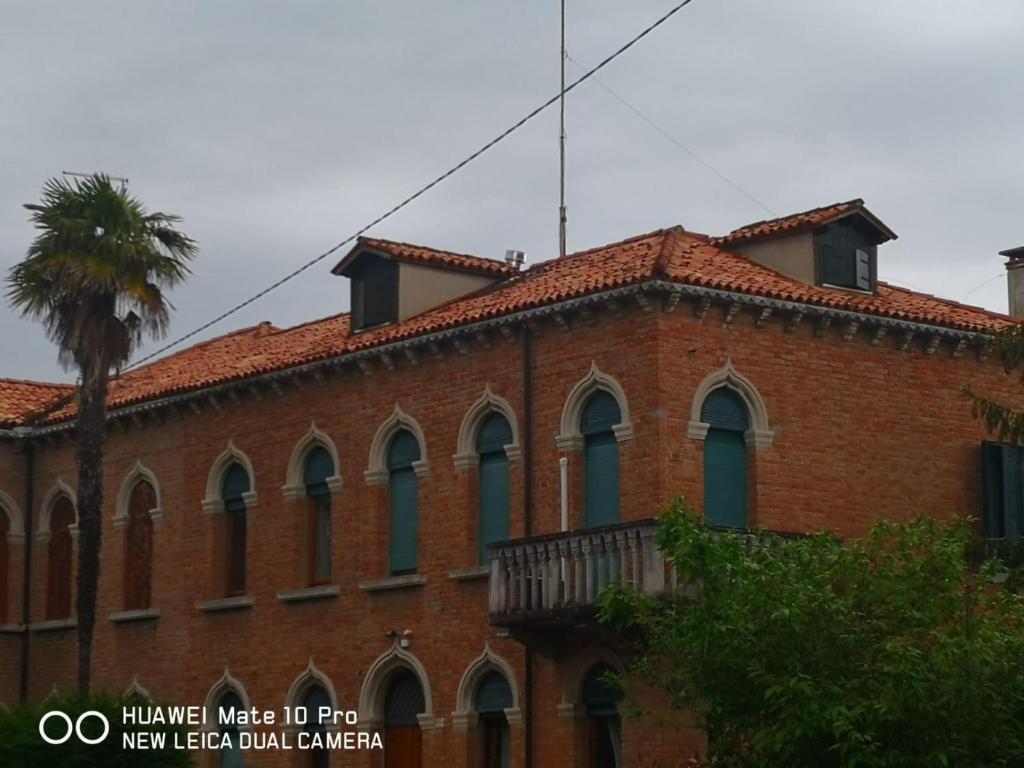 威尼斯丽都Cà ARIVANLIAL Venice villa apartament的一座红砖建筑,前面有一棵棕榈树