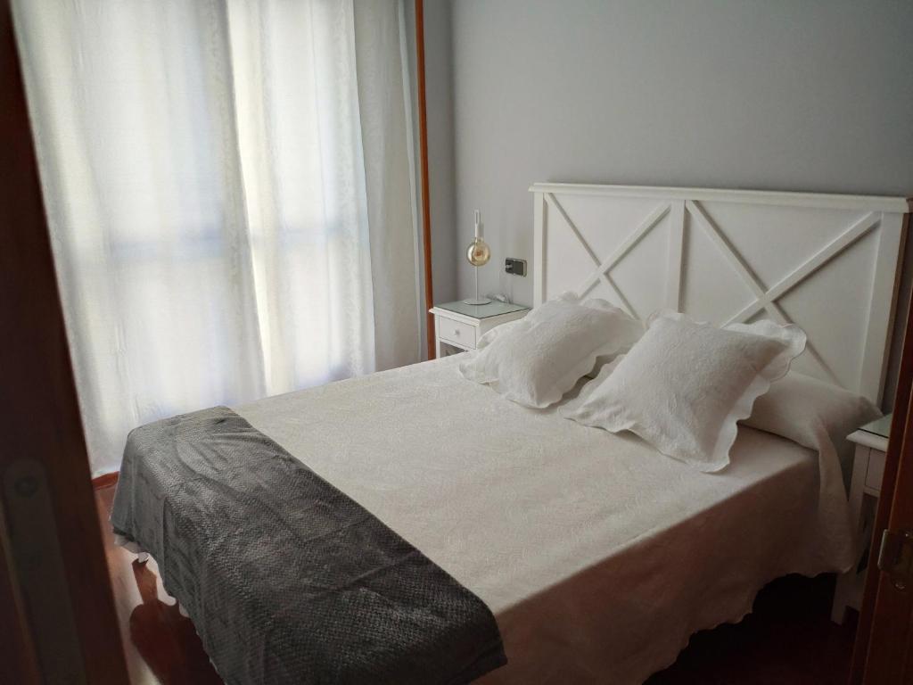 萨拉曼卡Apartamento Edificio Plaza Gran Vía的卧室配有带枕头的白色床和窗户。