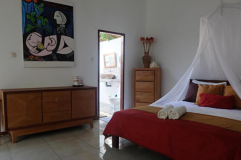 卡里蒙贾瓦卡里姆加瓦阿玉酒店的一间卧室配有一张带红色毯子的床和梳妆台
