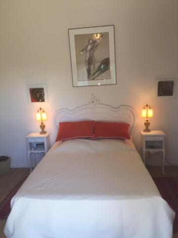 维逊拉洛梅尼L 'Havéli的一间卧室配有白色的床,两台桌子上有两个灯