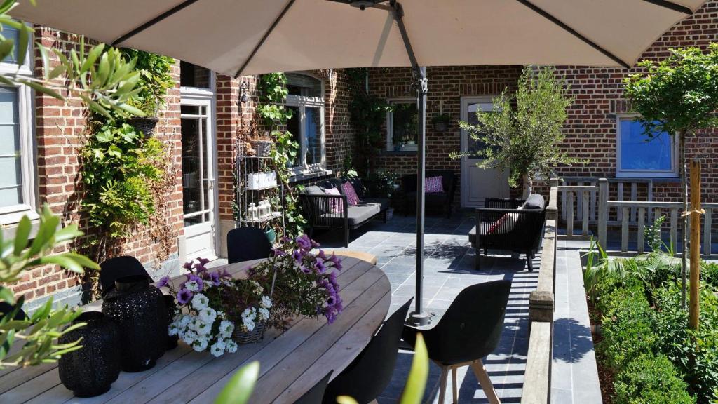 BoutersemGuesthouse Biolleke的一个带遮阳伞和鲜花长凳的庭院