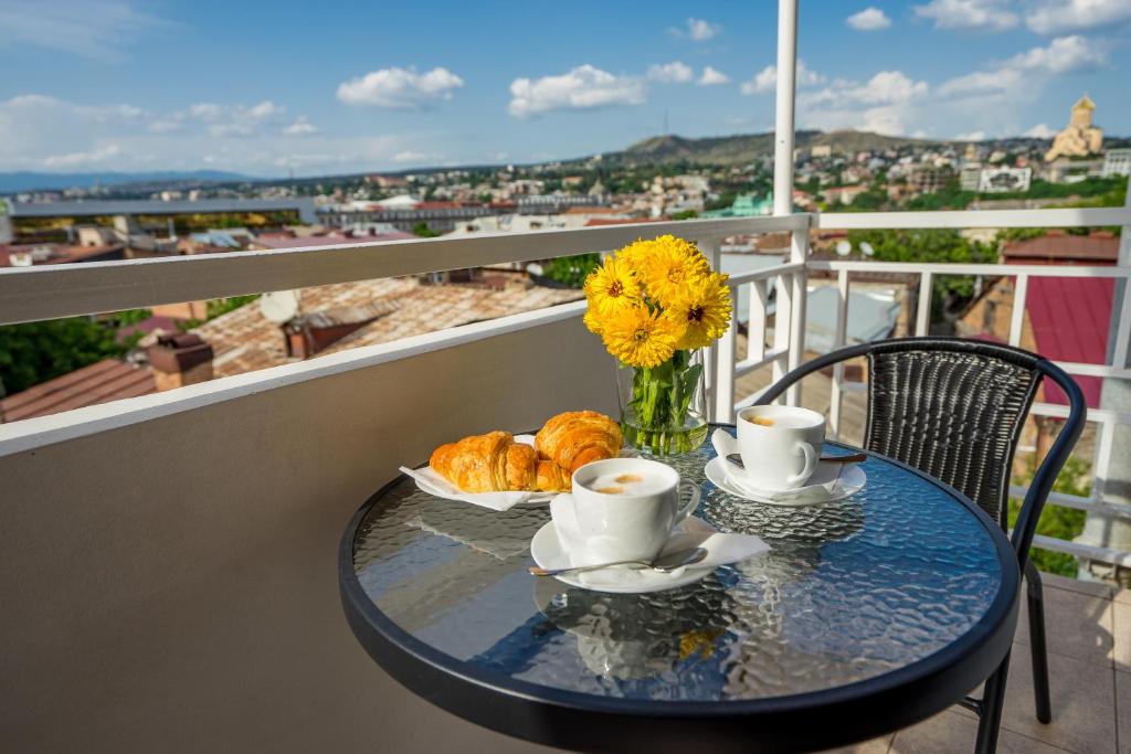 第比利斯Hotel Imperial House的阳台上的桌子上配有咖啡杯和羊角面包