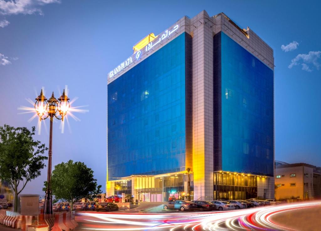 利雅德Grand Plaza Hotel - Gulf Riyadh的前面有汽车的蓝色大建筑
