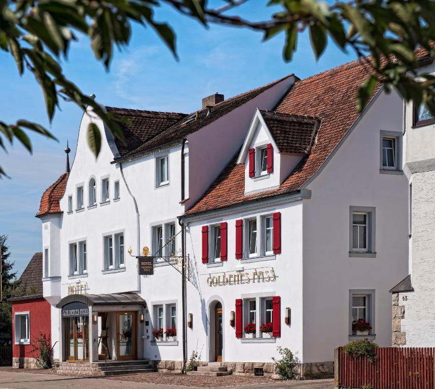 罗滕堡古登斯范斯TOP酒店的一座白色的大建筑,设有红色百叶窗