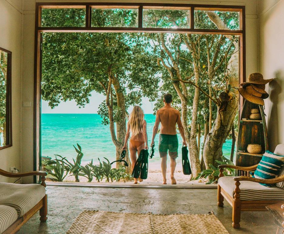 维拉港Whispering Palms - Absolute Beachfront Villas的站在一个看海洋的房间的男人和女人