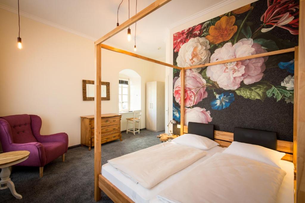 策尔廷根-拉蒂希德国庄园酒店的一间卧室配有一张天蓬床和一幅鲜花画
