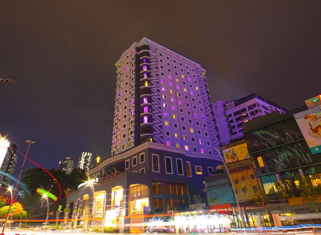 吉隆坡AnCasa Hotel Kuala Lumpur, Chinatown by AnCasa Hotels & Resorts的一座高大的建筑,上面有紫色的灯