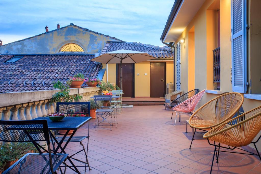 博洛尼亚Residence Studio Vita的庭院配有桌椅和遮阳伞。