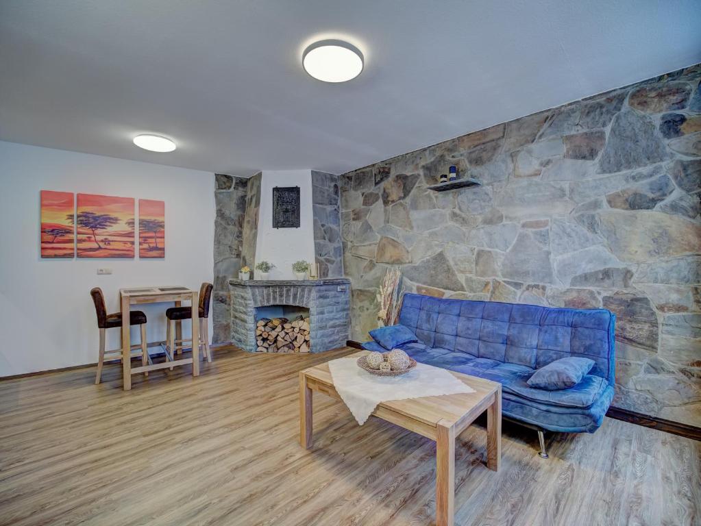 蒙绍Gästehaus Eschbach的客厅设有蓝色的沙发和石墙