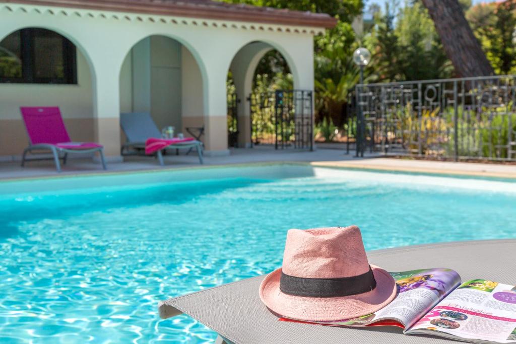 昂蒂布Ancre du Cap的游泳池旁椅子上的粉红色帽子