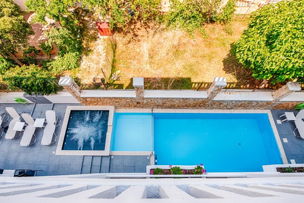 干尼亚亚历克西斯酒店 的蓝色游泳池,配有白色椅子和图片
