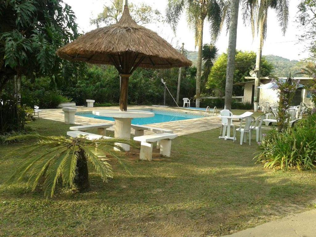 伊比乌纳Hotel Fazenda Bandeirantes的一个带野餐桌和遮阳伞的游泳池