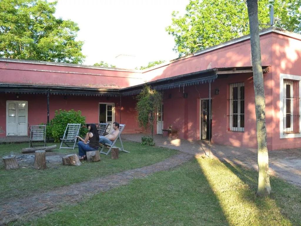 查斯科穆斯La Rosadita Casa de Campo的两人坐在红色房子外的椅子上
