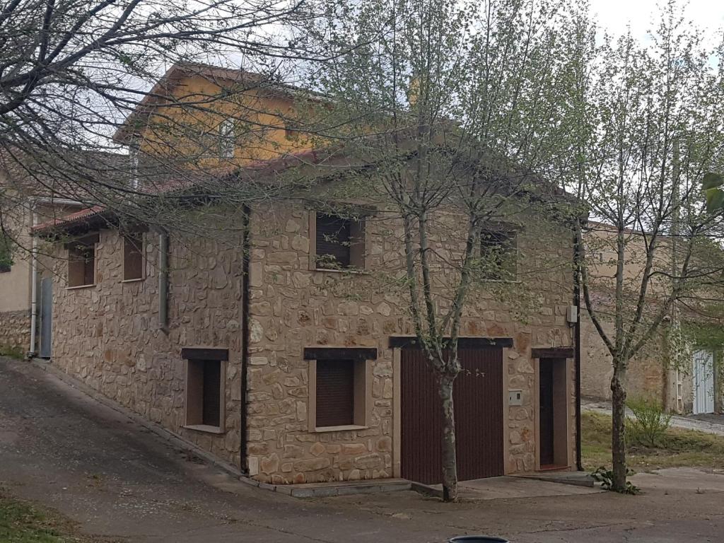 EstablésCasa Rural El Retiro de los Casasola的一座古老的砖砌建筑,前面有一棵树