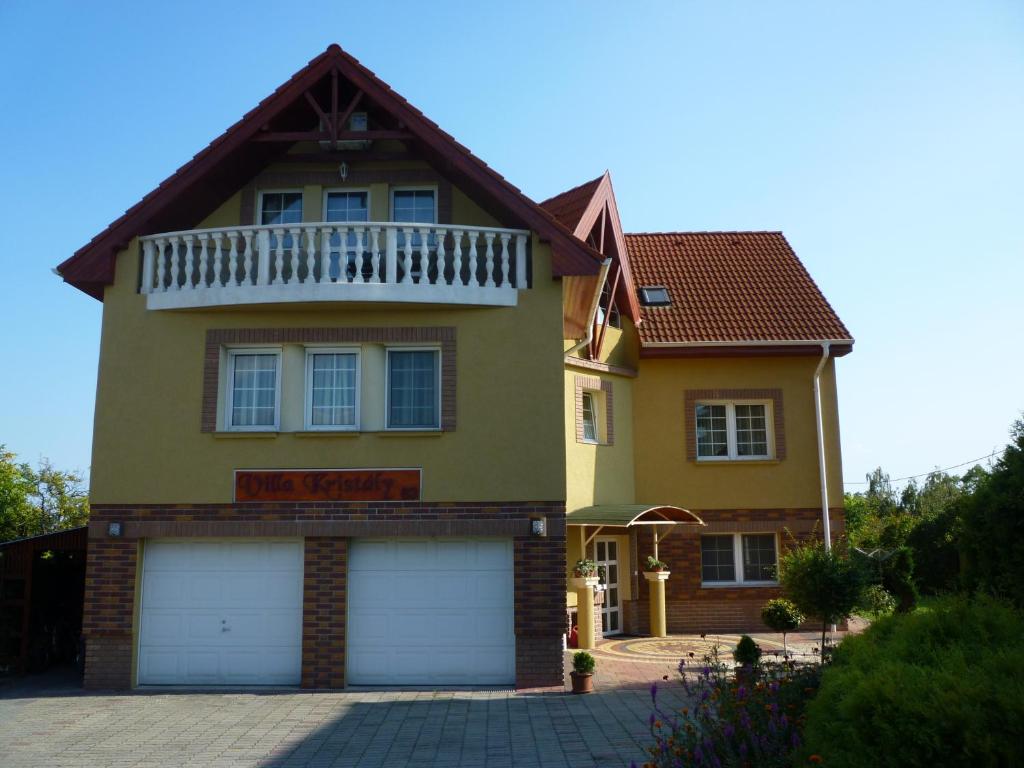 巴拉顿菲赖德Kristály Panoráma Villa的黄色的房子,前面有两扇车库门