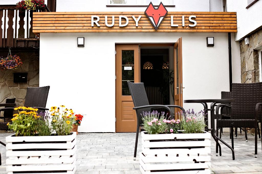 什切尔克Rudy Lis Szczyrk的一座建筑前带椅子和鲜花的庭院