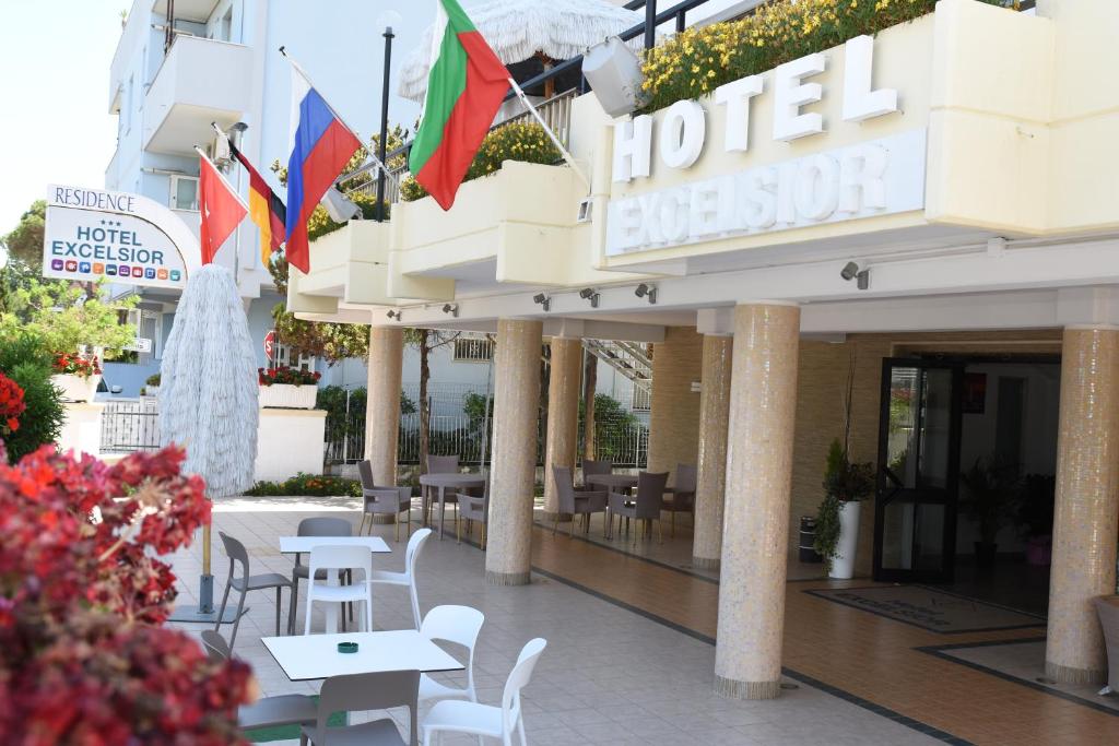 蒙特西尔瓦诺Hotel Excelsior的酒店入口处设有桌椅和旗帜