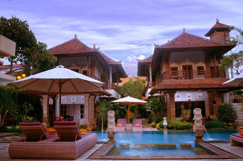 沙努尔普瑞沙丁酒店的一座带游泳池的度假村,位于一座建筑前