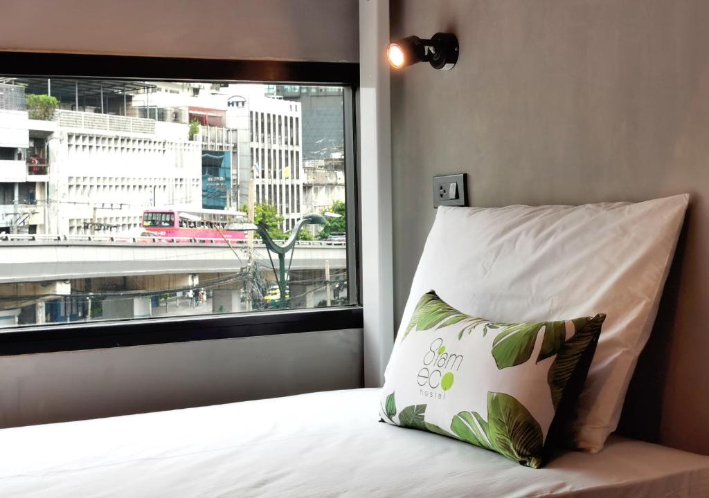 曼谷Siam Eco Hostel的窗户前带枕头的床