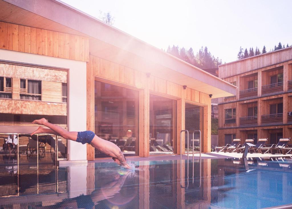 埃尔毛Tirol Lodge的一个人跳入建筑物旁边的游泳池