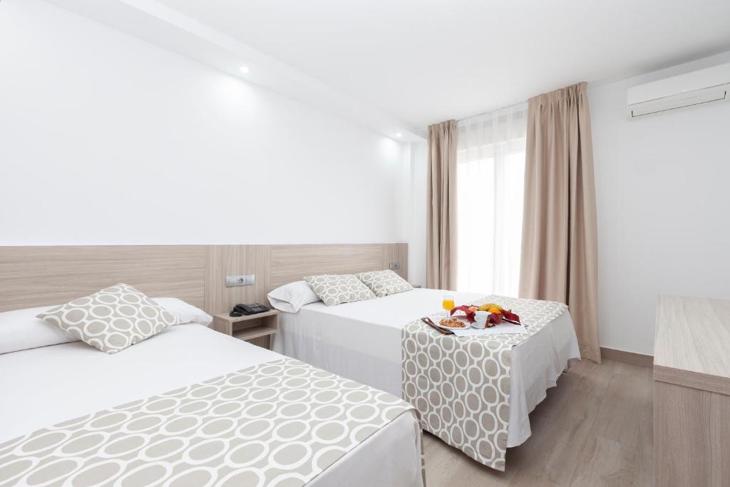 厄尔普伊格Hotel Olympia Ronda II的酒店客房设有两张床和一张桌子。