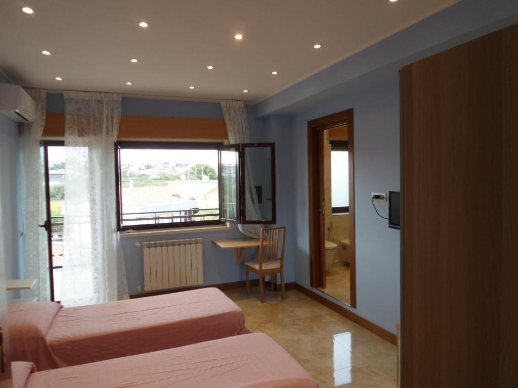 格拉维纳迪卡塔尼亚b&b aurora的客房设有两张床、一张桌子和一扇窗户。