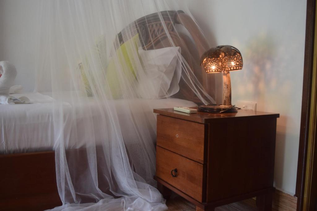 拉迪格岛绿竹小屋旅馆的一间卧室配有一张床,梳妆台上配有一盏灯