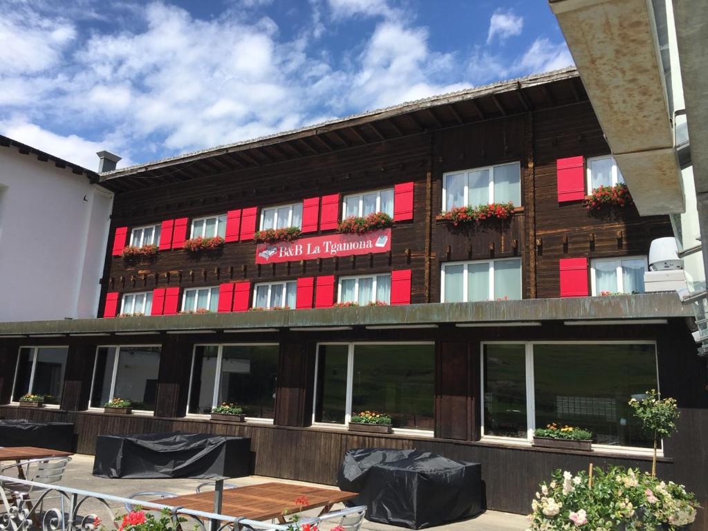 萨沃宁B&B La Tgamona的酒店前面设有红色窗户和桌子