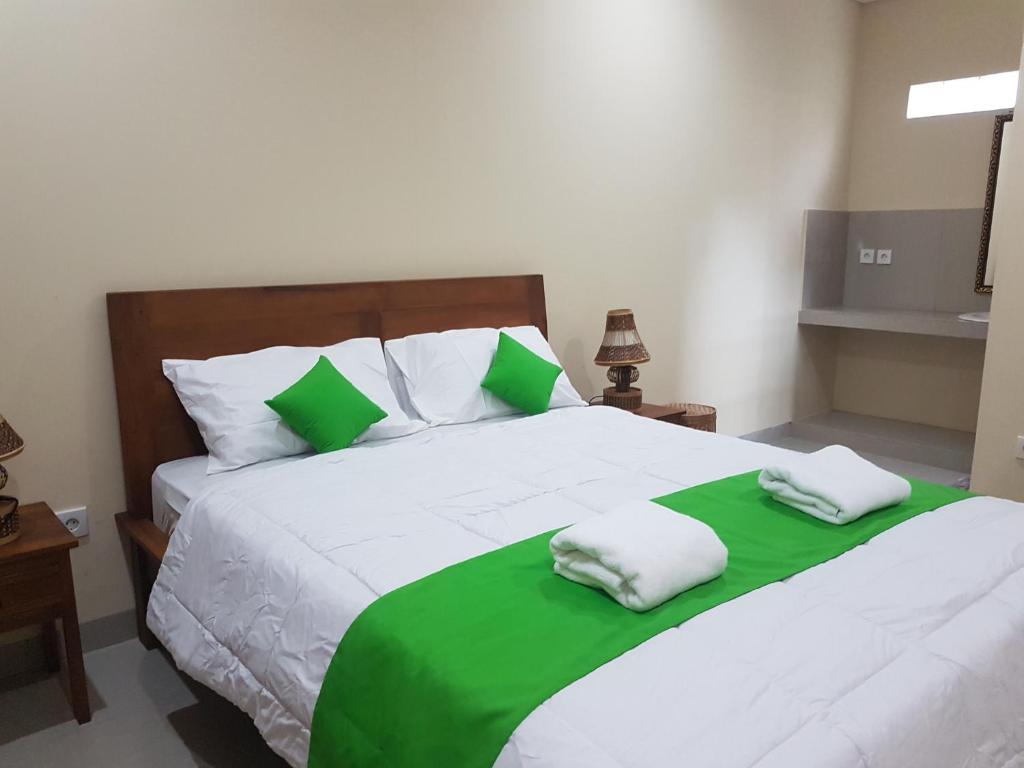 乌布Gusti Room的一间卧室配有一张带绿色和白色床单的大床