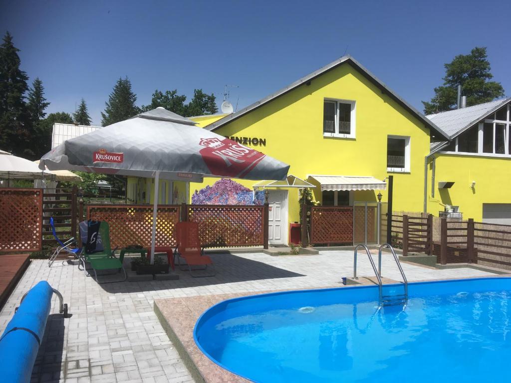 Krásný DvŭrPenzion Krásný Dvůr的黄色房子前面的游泳池
