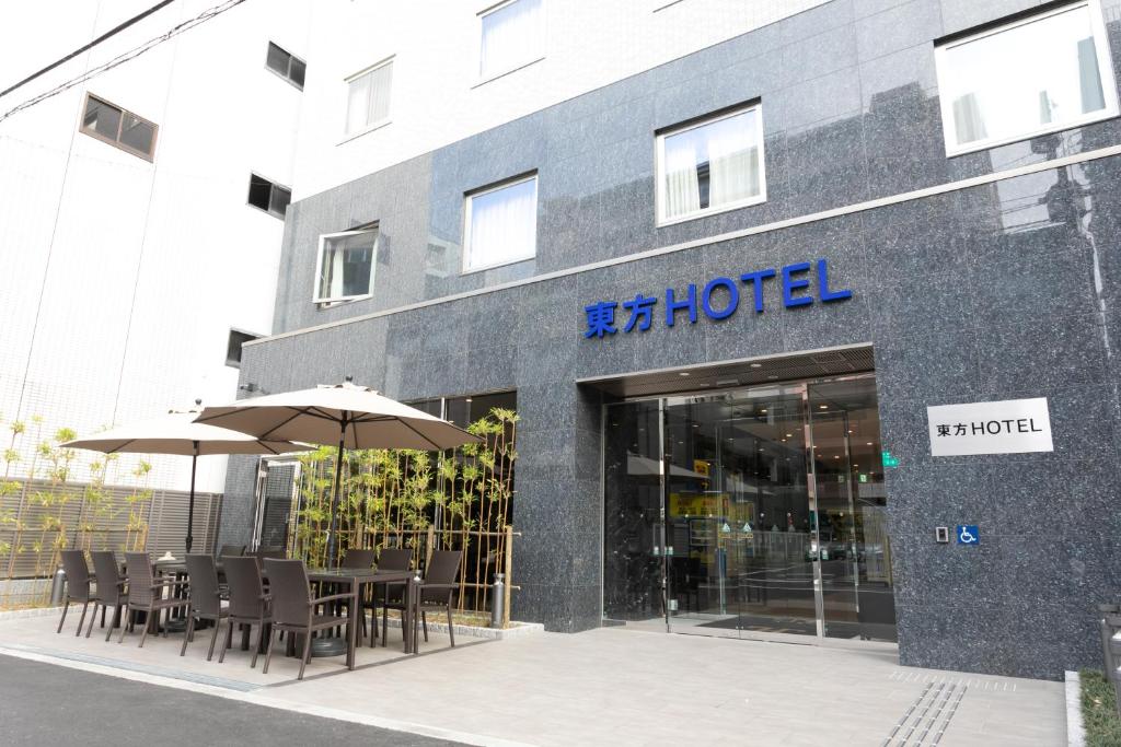 大阪Toho Hotel Namba Motomachi的前面设有桌子和遮阳伞的酒店