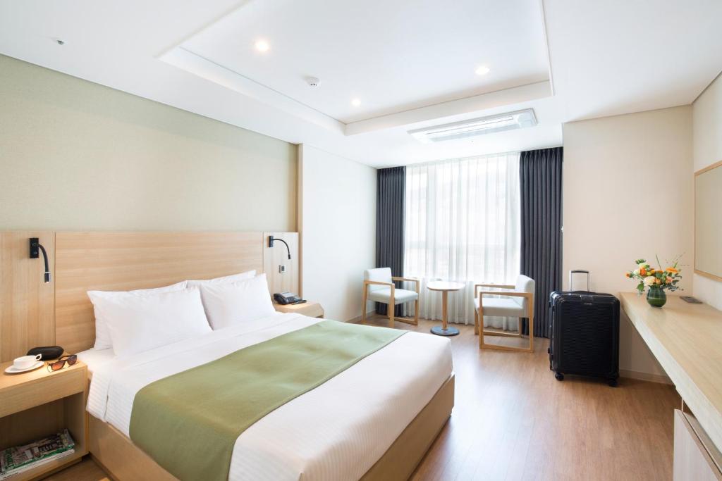 釜山釜山皇冠海港酒店的酒店客房带一张床、一张桌子和椅子