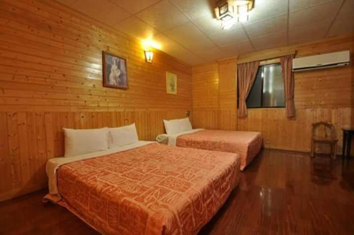 车城四重溪洺泉溫泉旅館的木制客房内的一间卧室配有两张床
