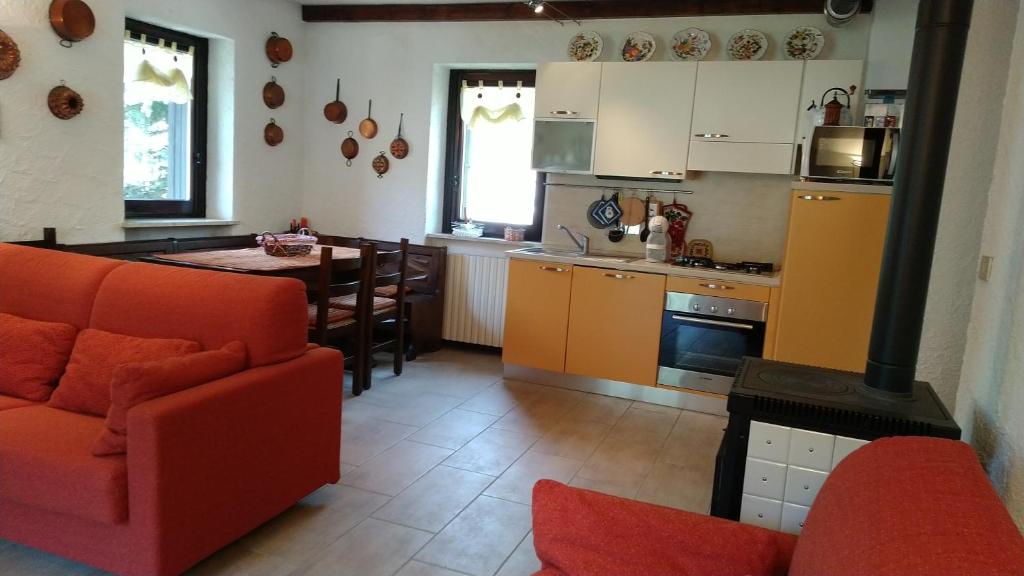 普拉吉拉托La Segheria的一间带红色沙发的客厅和一间厨房