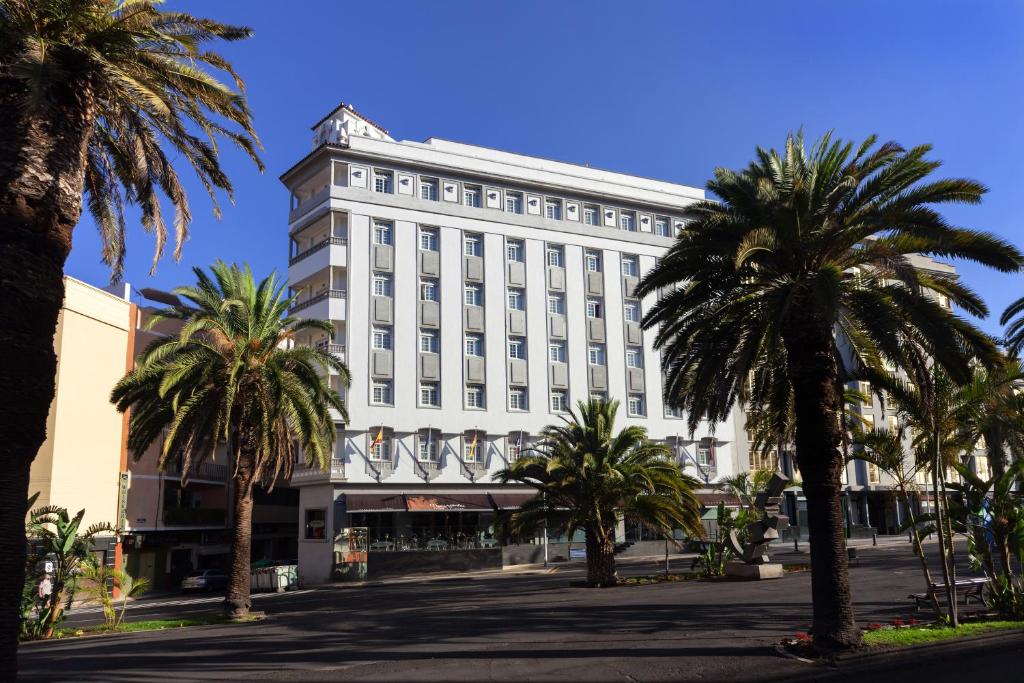 圣克鲁斯-德特内里费圣克鲁斯现代公寓的一座白色的大建筑,前面有棕榈树