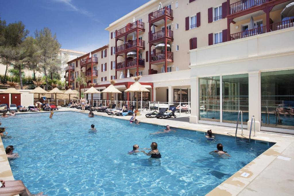 滨海卡瓦莱尔Résidence Prestige Odalys Les Canissons的一群人在酒店的游泳池里