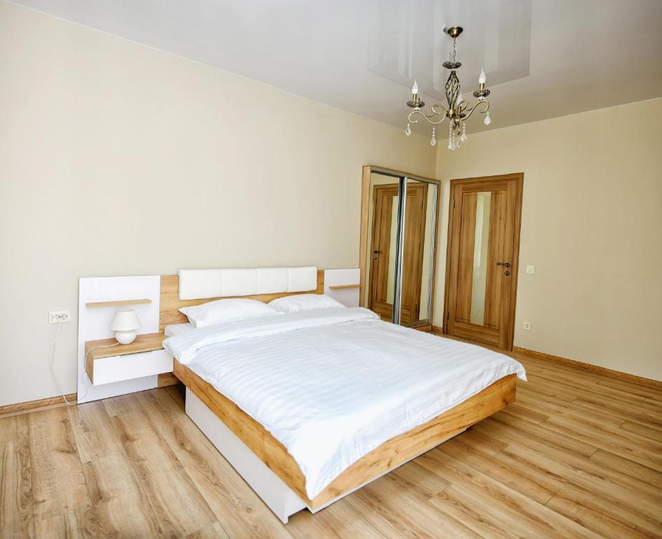 伊万诺-弗兰科夫斯克Apart Reserve Sloboda Klassik的白色卧室配有一张大床和吊灯