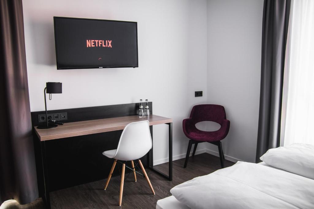 菲尔德施塔特Hayta Hotel Stuttgart Airport Messe的一间卧室配有书桌、电视和椅子
