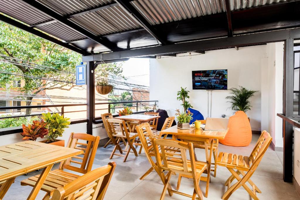 麦德林Medellin Backpacker Hostel的一间带木桌和椅子的餐厅以及一个阳台