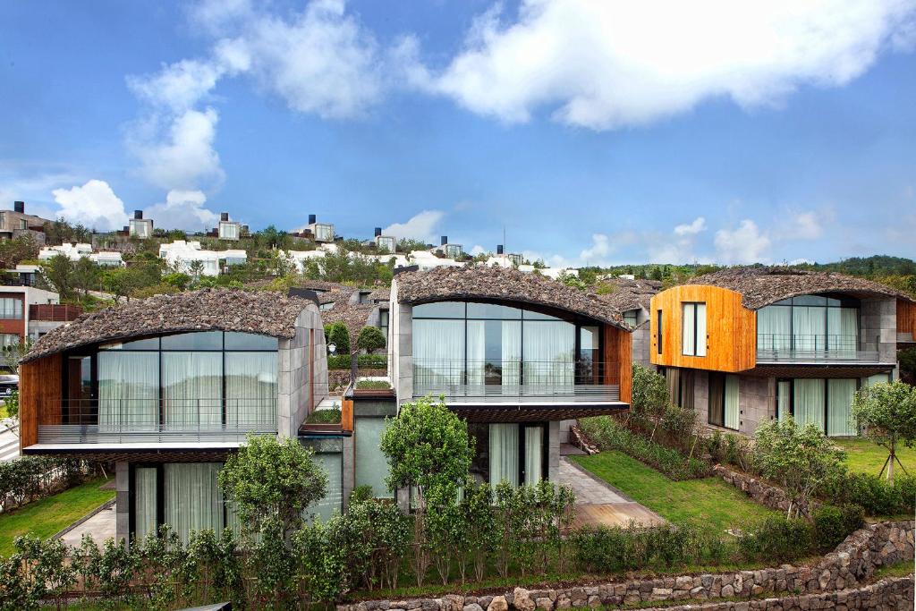 西归浦市Lotte Resort Jeju Artvillas的山顶上带窗户的大房子