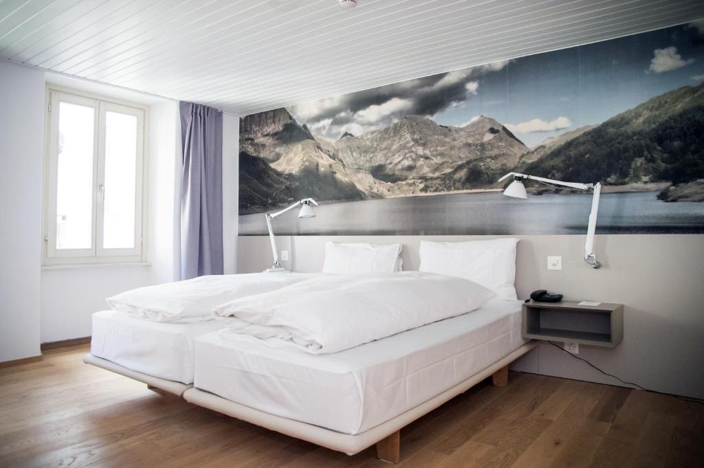 艾罗洛Hotel & Restaurant Forni的卧室配有一张白色大床,墙上挂有绘画作品